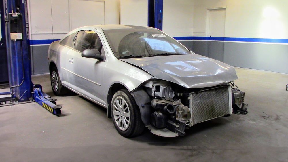Chevrolet Cobalt donor car in a shop bay with front bumper removed