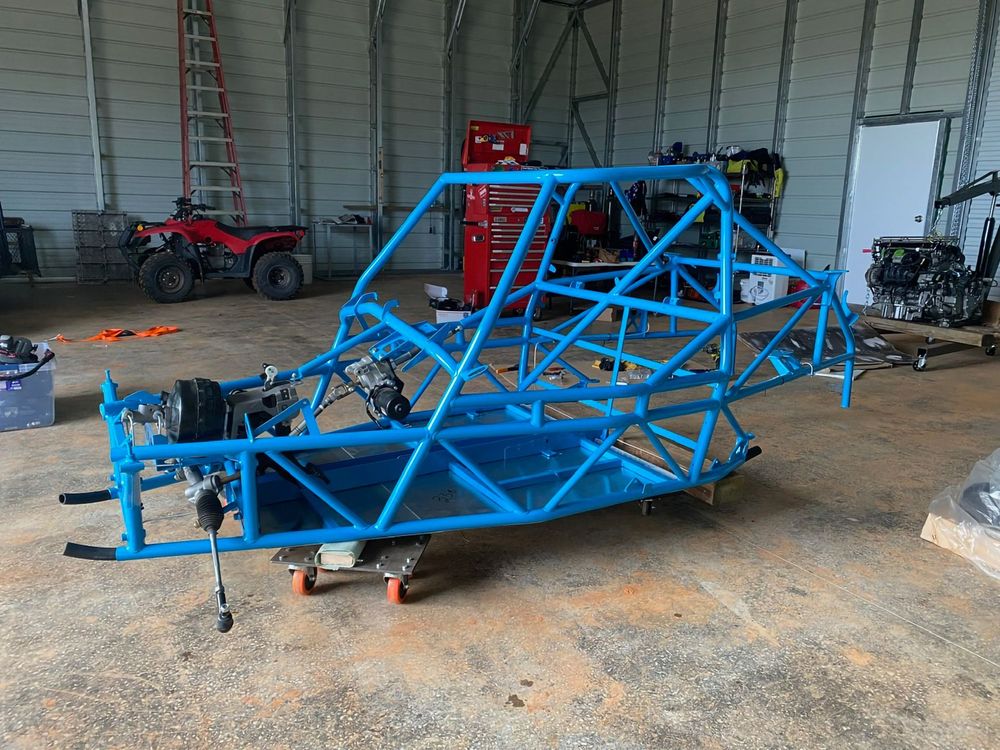 Freshly coated blue DF Goblin V1 chassis on dollies in a workshop, showing suspension mounts and frame layout.