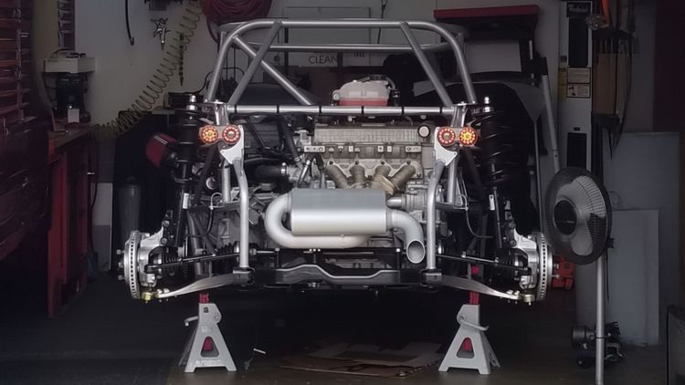 Partially built DF Goblin #39 on jack stands in a single car garage, viewed from the rear showing the engine and suspension.