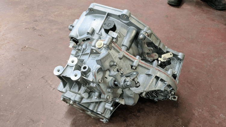 Chevrolet Cobalt F23 transmission showing flat stamped end cover, two shifter counterweights, and mount holes aligned on the same plane.