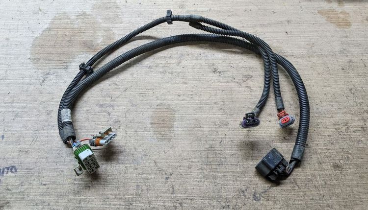 Fuel pump wiring harness from a Cobalt donor, with connector ends and protective loom visible on a workbench.