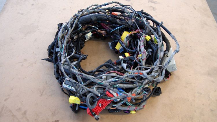 Main wiring harness from a Chevrolet Cobalt donor, coiled on a shop floor with connectors visible.