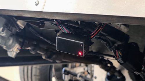 Macchina A0 Bluetooth OBD-II dongle plugged into the OBD-II port of a donor Mk7 GTI system, with the red status LED illuminated during the IMMO delete flash.