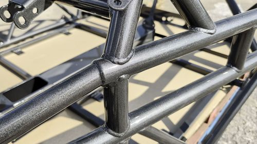 Close-up of the Crystal Grey powder coat on V2-006 showing the silver metallic flake and clear coat over a welded chassis joint